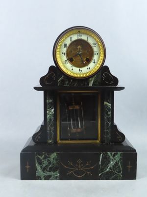 une horloge noire et dorée posée sur un socle en marbre