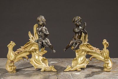 pair of antique bronze figurines of cherensils on a marble table
