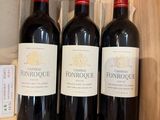 trois bouteilles de vin rouge sont posées dans une caisse en bois sur une étagère