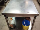 a stainless steel table with a bucket on it in the middle of a kitchen