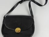 a black purse with a gold button on it sitting on a white surface