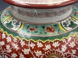 un vase rouge orné d'un motif vert et jaune