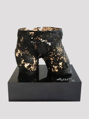 black and gold sculpture of a pair of boots on a black base