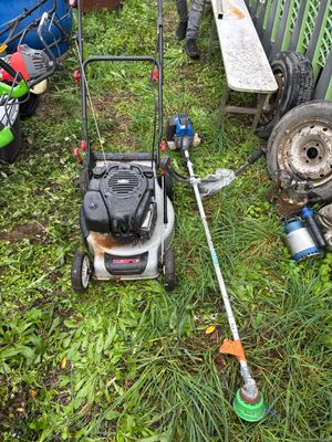 une tondeuse à gazon posée dans l'herbe, près d'une clôture