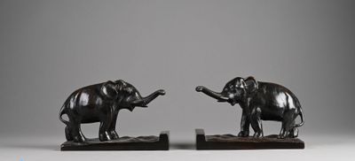 pair of bronze elephants on wooden bases on a gray background