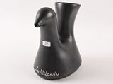 un vase noir orné d'une anse en forme d'oiseau sur fond blanc