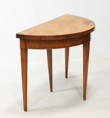 une petite table en bois au plateau incurvé, posée sur un sol blanc