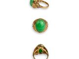 three gold rings with green stones on them on a white surface