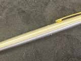 silver and gold ballpoint pen laying on a black surface