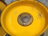 a yellow trash can with a metal strainer in it