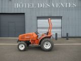 un petit tracteur orange garé devant un bâtiment