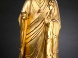 statue of a golden buddha on a wooden base with a black background