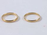 two gold wedding rings on a white surface