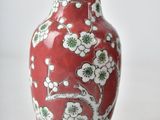 a red vase with white flowers on it sitting on a table