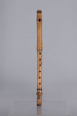 a wooden flute on a clear surface with a gray background