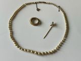 un collier de perles, accompagné d'une bague et d'une broche, posé sur un fond blanc
