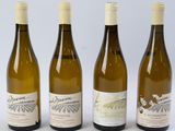 quatre bouteilles de vin sont alignées sur une surface blanche