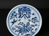 blue and white plate with flowers and birds on it on a black surface
