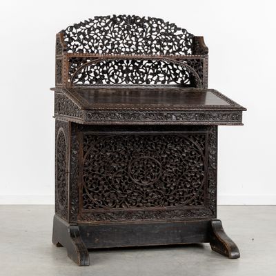 an old wooden table with a carved top on a cement floor