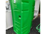 a green portable toilet sitting on top of a gravel ground