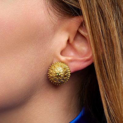a close up of a woman wearing a blue shirt and gold earrings