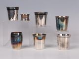 several silver cups are lined up in a row on a white surface