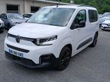 une camionnette blanche garée sur un parking, avec d'autres voitures en arrière-plan