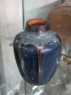 a blue vase on display in a glass case