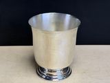 a silver cup sitting on a table with a black background