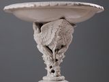 a sculpture of a bird on a pedestal with a bowl on it