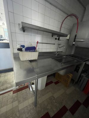 une cuisine équipée d'un évier et d'un plan de travail sur lequel est posé un seau