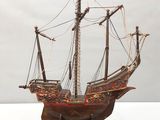 une maquette de bateau posée sur un socle, sur une surface blanche