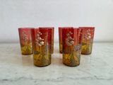 quatre verres rouges ornés de motifs dorés, posés sur un plan de travail en marbre