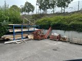 un tas de bois sur un parking, près d'une clôture