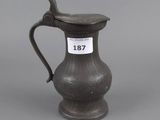 an antique pewware pitcher with a bird on the handle