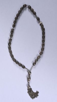 un gros plan d'un collier orné d'un pompon, posé sur une surface blanche