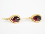 une paire de boucles d'oreilles ornées de grenats rouges sur fond blanc