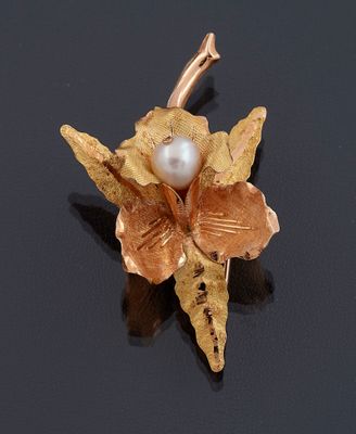 une broche en forme de fleur, en perles et en or, sur un fond noir