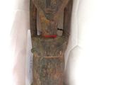 une vieille statue en bois d'un homme avec un chapeau sur la tête