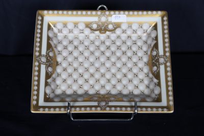 une assiette blanche et dorée ornée de perles