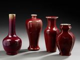 trois vases rouges posés les uns à côté des autres sur une table