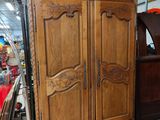 a wooden armoire in the middle of a room filled with furniture
