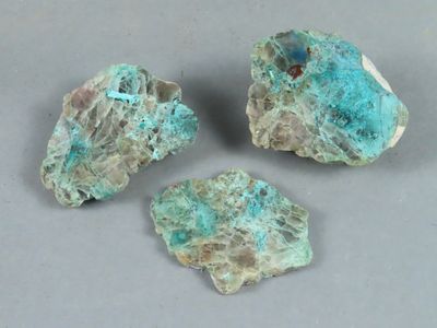 trois morceaux de roche de couleur turquoise posés sur une surface grise