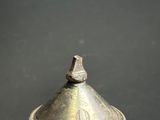 a silver vase with a bird on top of it
