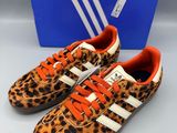une paire de baskets Adidas à imprimé léopard devant une boîte bleue