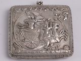 une boîte ancienne en argent sur laquelle figure l'image d'un homme dans une calèche tirée par un cheval