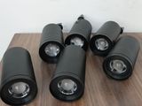 six projecteurs à LED noirs posés sur une table en bois, devant un mur blanc