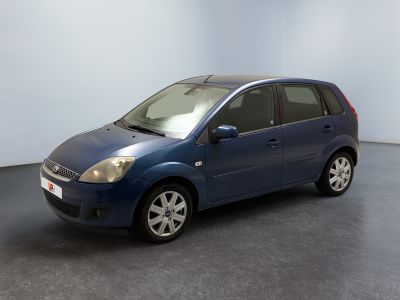 une voiture bleue garée dans une pièce aux murs blancs et au sol noir