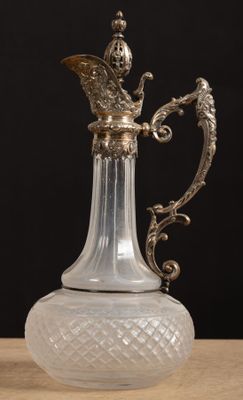un vase en verre muni d'une poignée en métal, posé sur une table