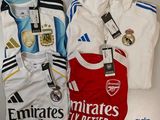 Trois maillots de football sont posés sur une table, avec leurs étiquettes encore attachées.
